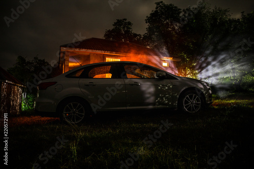 The car in the shadows with glowing lights in low light, or silhouette of sport car dark background. Selective focus