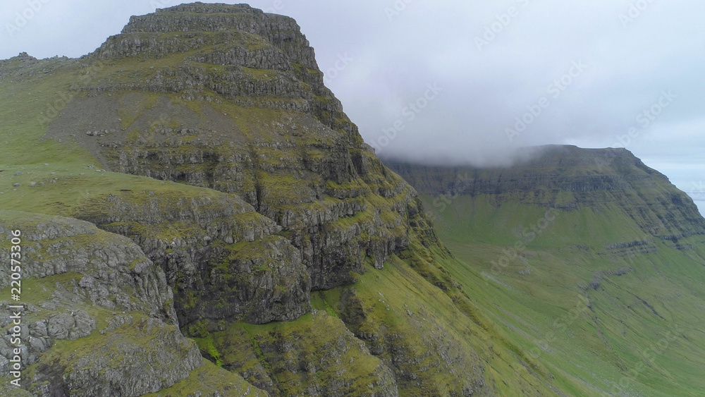 AERIAL: Flying towards cliff covered in grass in the wilderness of Faroe Islands AERIAL: Flying towards cliff covered in grass in the wilderness of Faroe Islands