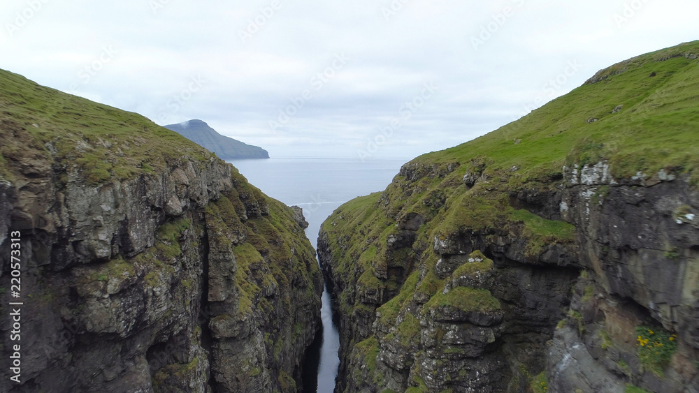 AERIAL: Flying along a narrow rocky gorge leading towards the vast open seas.