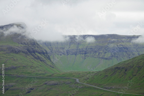 AERIAL: Flying towards an empty concrete road winding through grassy landscape.