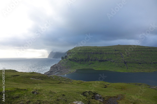Large storm clouds gather over the picturesque cliffs and ocean in Faroe Islands
