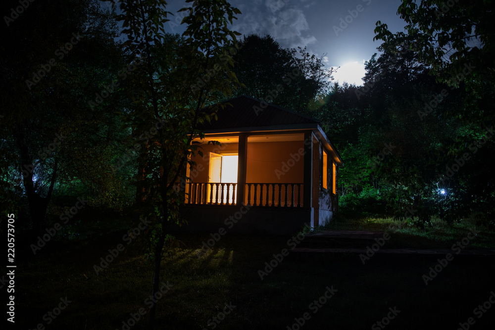 Mountain night landscape of building at forest at night with moon or vintage country house at night with clouds and stars. Summer night. Mountain night landscape of building at forest at night with moon or vintage country house at night with clouds and stars. Summer night.