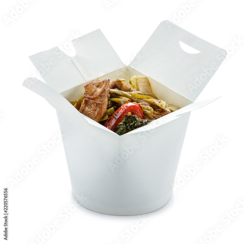 Spinach noodles with chicken and vegetables in take-out box over white. With path.