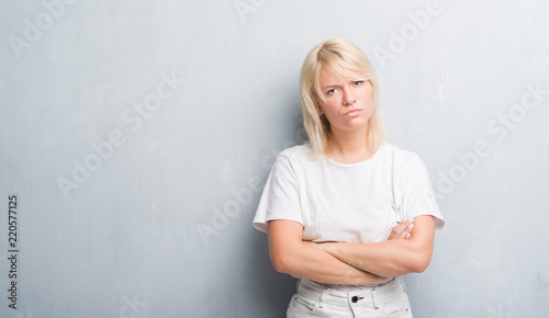 Adult caucasian woman over grunge grey wall skeptic and nervous, disapproving expression on face with crossed arms. Negative person.