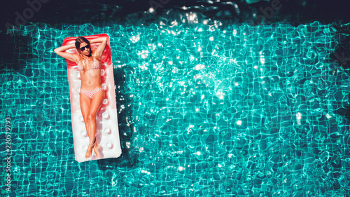 Fotografi Young pretty slim woman on a pink air mattress in the swimming pool