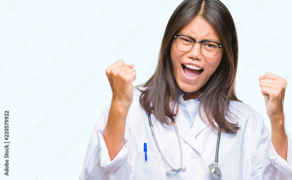 Young asian doctor woman over isolated background very happy and excited doing winner gesture with arms raised, smiling and screaming for success. Celebration concept. Young asian doctor woman over isolated background very happy and excited doing winner gesture with arms raised, smiling and screaming for success. Celebration concept.
