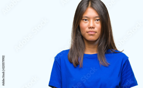 Young asian woman over isolated background with serious expression on face. Simple and natural looking at the camera. © Krakenimages.com