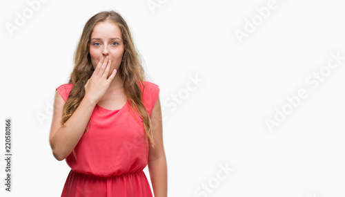 Young blonde woman wearing pink dress cover mouth with hand shocked with shame for mistake, expression of fear, scared in silence, secret concept