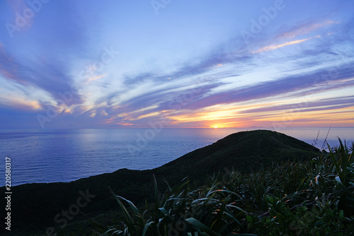 Sunset over Cape Reinga (Te Rerenga Wairua), the northwesternmost tip of the Aupouri Peninsula, at the northern end of the North Island of New Zealand, where the Tasman Sea meets the Pacific Ocean photo