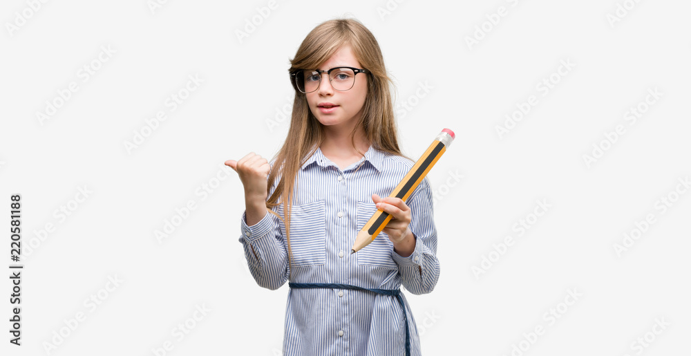 Young blonde child holding big pencil pointing with hand and finger up with happy face smiling Young blonde child holding big pencil pointing with hand and finger up with happy face smiling