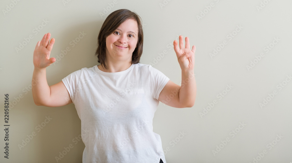 Down syndrome woman standing over wall showing and pointing up with fingers number nine while smiling confident and happy. Down syndrome woman standing over wall showing and pointing up with fingers number nine while smiling confident and happy.
