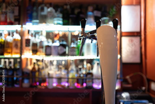 Close focus of beer tap in restaurant bar with shelves of alcohol blurred in background