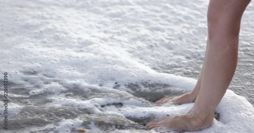 Beautiful hip young woman on beach - hands and feet in ocean - close up Beautiful hip young woman on beach - hands and feet in ocean - close up