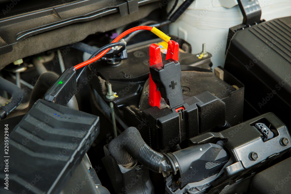 Engine engineer is recharging car battery because car battery is depleted. concept car maintenance.Selective focus charging car with electricity trough cables Engine engineer is recharging car battery because car battery is depleted. concept car maintenance.Selective focus charging car with electricity trough cables