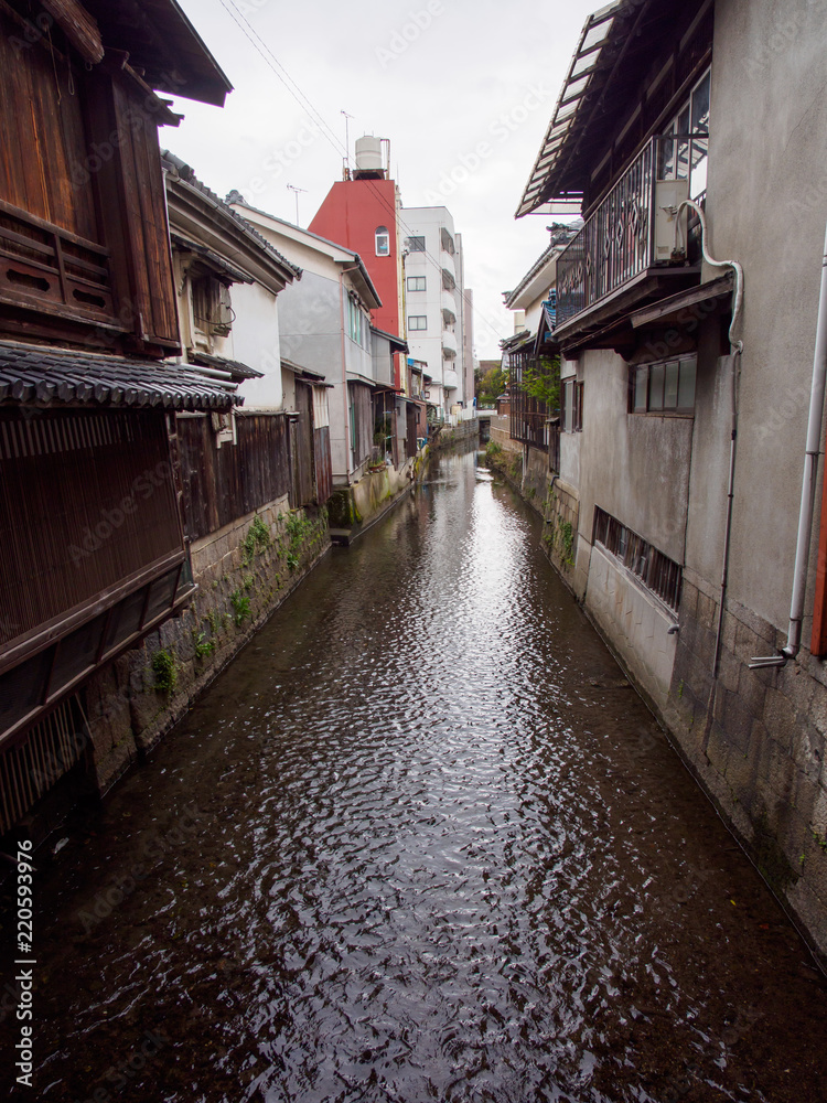 Wide vertical view of multiple concrete buildings and traditional wooden houses along the canals of Kurokabe residential district. Nagahama, Shiga, Japan. Travel and architecture