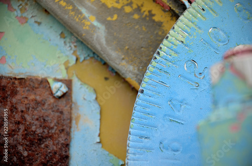 Closeup of rusted gear on machine with chipping blue and yellow paint