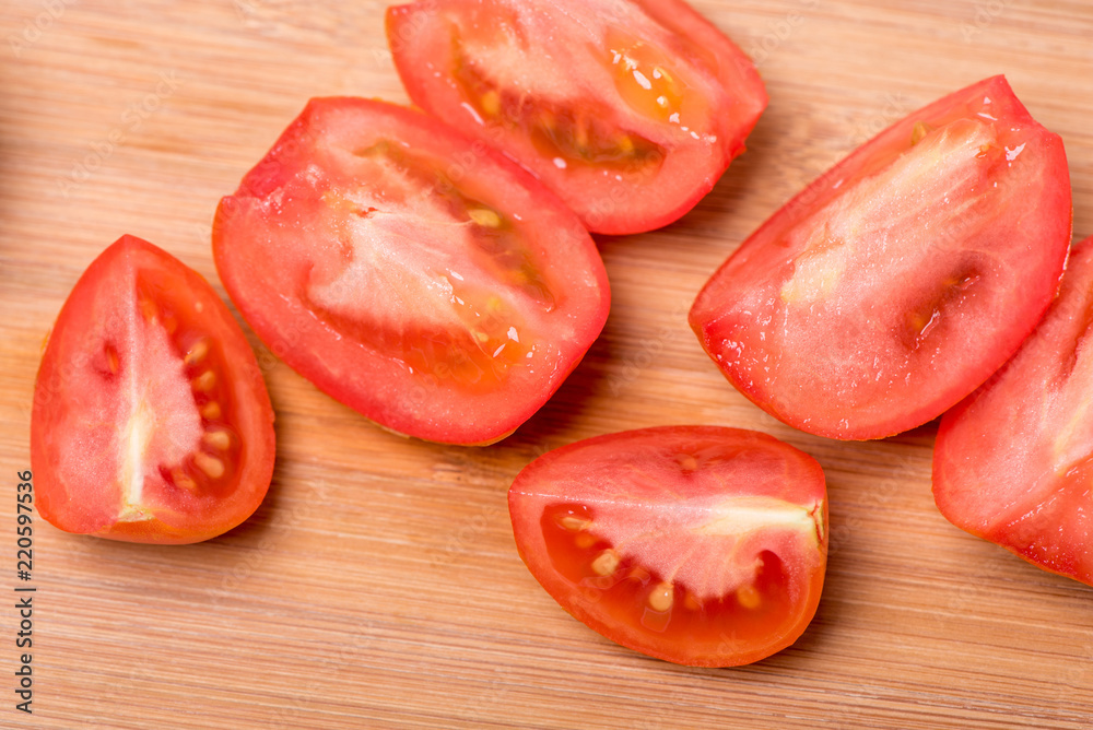 Juicy red tomato chopped on a wooden board on a white background