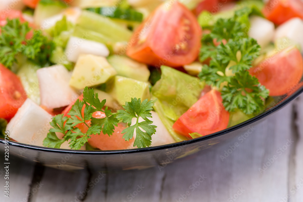 Delicious salad of vegetables, turnips, cucumber, tomato, avocado and parsley on a white background Delicious salad of vegetables, turnips, cucumber, tomato, avocado and parsley on a white background