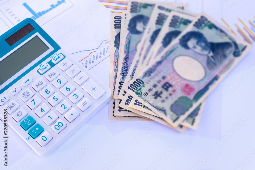 Fototapeta premium Calculator with blurred Japanese currency yen bank notes and coin on finance chart and graph background, finance planning concept