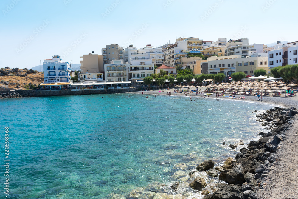 Agios Nikolaos. Crete. Vacationers on the beach at the waterfront Akti PapaNikolaou Pagkalou