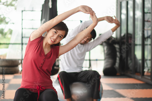 Healthy workout. Young cheerful woman sitting on the yoga mat and exercising with ball in the gym.