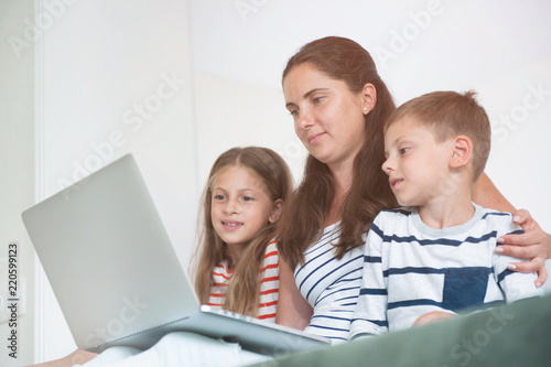 beautiful family mother and children watching on laptop screen internet online