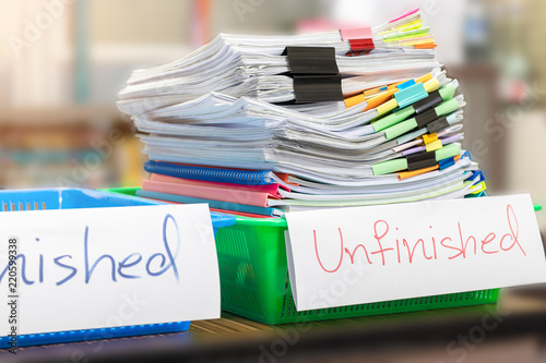 Pile of unfinished document on office desk. Stack of homework assignment archive with colorful paper and paper clip on teacher's table waiting to be managed and checked. Education and business concept