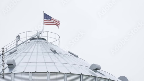 American flag on farm grain silo waving in the wind