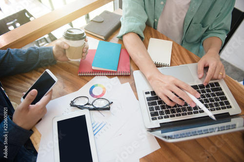 business team  briefing marketing strategy with smart phone, tablet, notebook, and laptop on wooden desk with,Freelance work at home office. Writing note on a book. photo