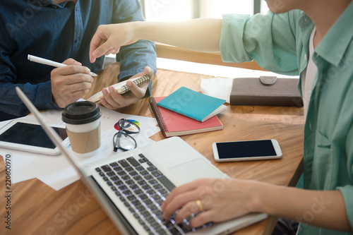 business team  briefing marketing strategy with smart phone, tablet, notebook, and laptop on wooden desk with,Freelance work at home office. Writing note on a book.
