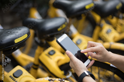People hands using smartphone scanning the QR code of shared bike in city photo