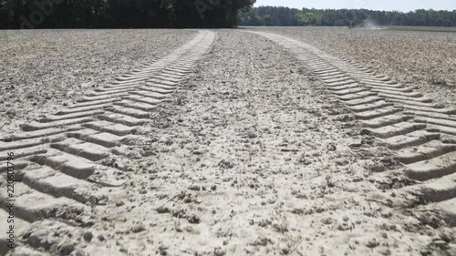 Large tire tracks in field with tractor in the background