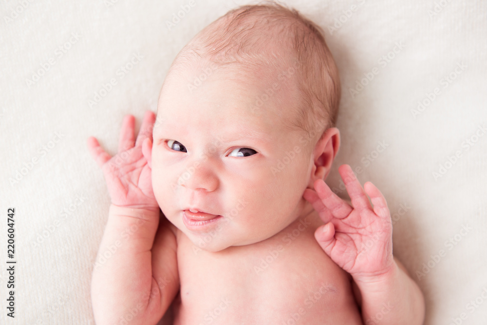 Newborn baby looking surprised at the camera in white bed. Family, new life, childhood, beginning concept Newborn baby looking surprised at the camera in white bed. Family, new life, childhood, beginning concept