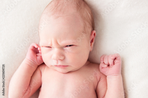 Newborn baby looking surprised at the camera in white bed. Family, new life, childhood, beginning concept