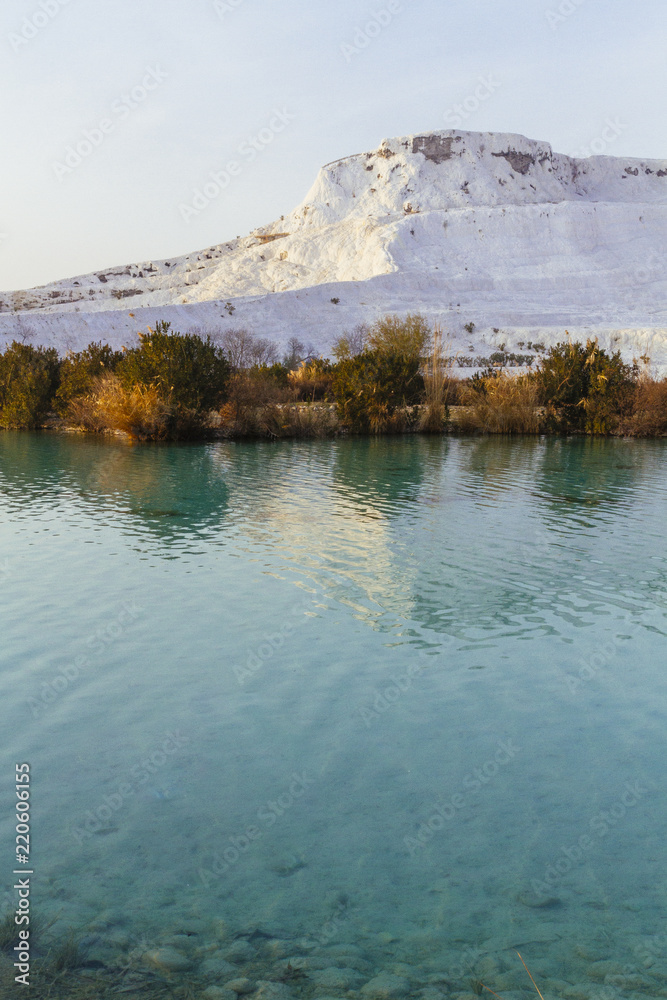 Obraz premium White travertine limestone mountain and its reflection in the lake in Pamukkale, Turkey