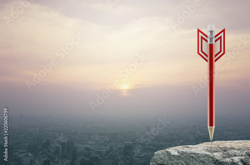Red pencil in the shape of a dart on rock stone over aerial view of cityscape at sunset, vintage style, Business or industry strategy concept