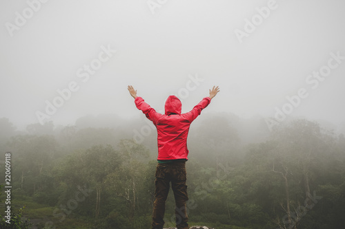 Traveler Man raised hands standing on cliff mountains adventure travel lifestyle concept summer vacations outdoor euphoria happy emotions © khlongwangchao