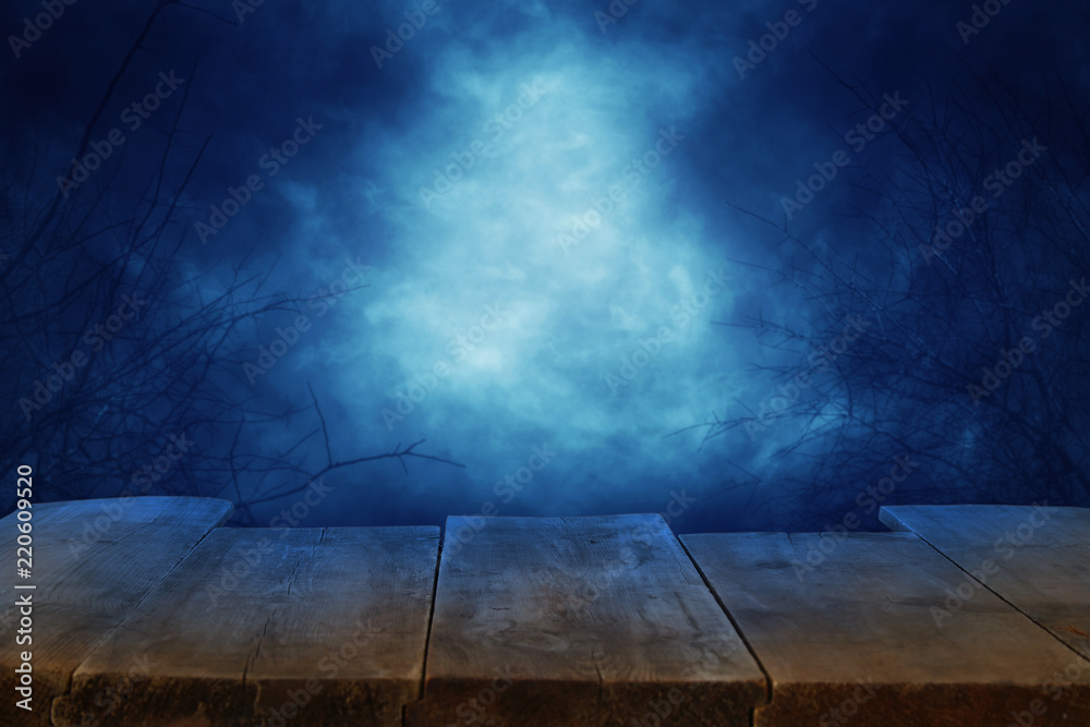 Fototapeta premium Halloween holiday concept. Empty rustic table in front of scary and misty night sky background. Ready for product display montage.