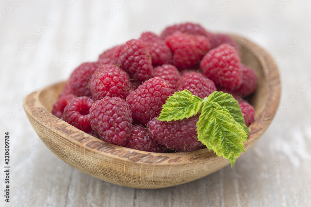raspberry in a wooden plate on a kitchen table. raspberry in a wooden plate on a kitchen table.