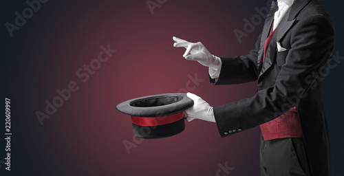 Illusionist white hand wants to conjure with magic wand from a black cylinder something photo