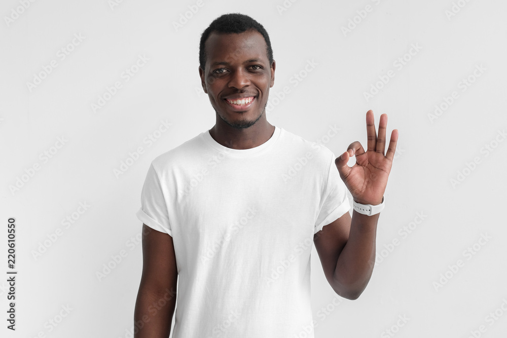 Fototapeta premium Young black man having happy look, smiling, gesturing, showing OK sign. African male showing OK-gesture with his fingers. Body language concept
