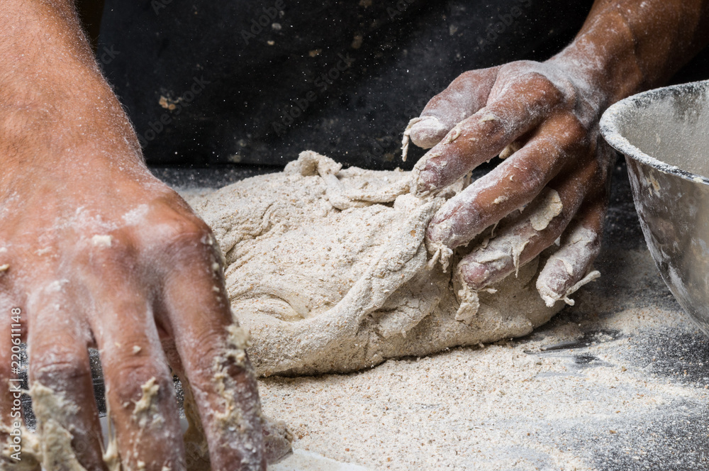 Fototapeta premium Male hands kneading dough on sprinkled
