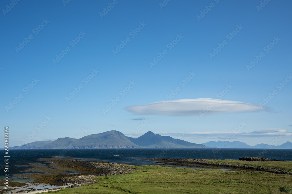 The island of Rum, with a lenticular cloud, as viewed from the Isle of Muck.  Rum, on the west coast of Scotland, is a National Nature Reserve, home to a diverse range of wildlife.