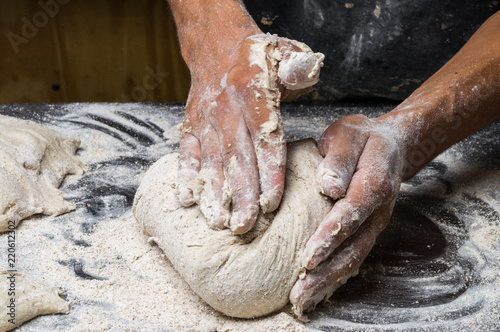 Male hands kneading dough on sprinkled