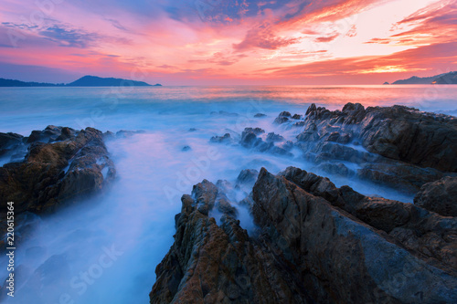 Long exposure image of Dramatic sky and wave seascape with rock in sunset scenery background.