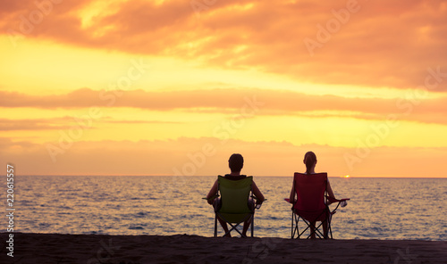 Couple siting on the beach watching the sunset. 