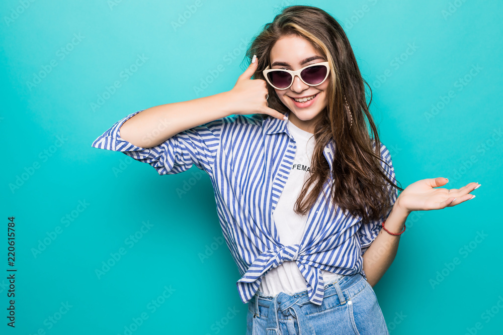 Portrait of attractive happy girl with glasses gesturing with fingers call me isolated on blue background Portrait of attractive happy girl with glasses gesturing with fingers call me isolated on blue background