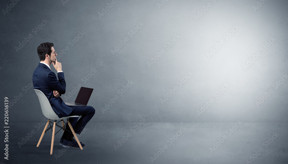 Αυτοκόλλητο Businessman staying in an empty grey dark room with stuffs on his lap