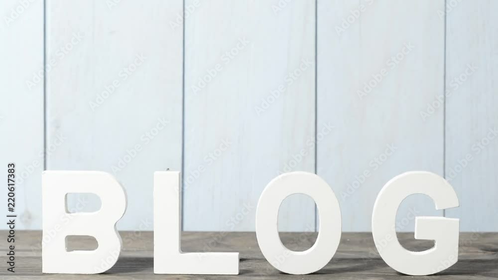BLOG escrito en letras de madera blanca sobre la mesa de madera gris y pared azul