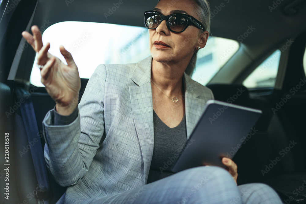 Mature businesswoman sitting on back seat of a car
